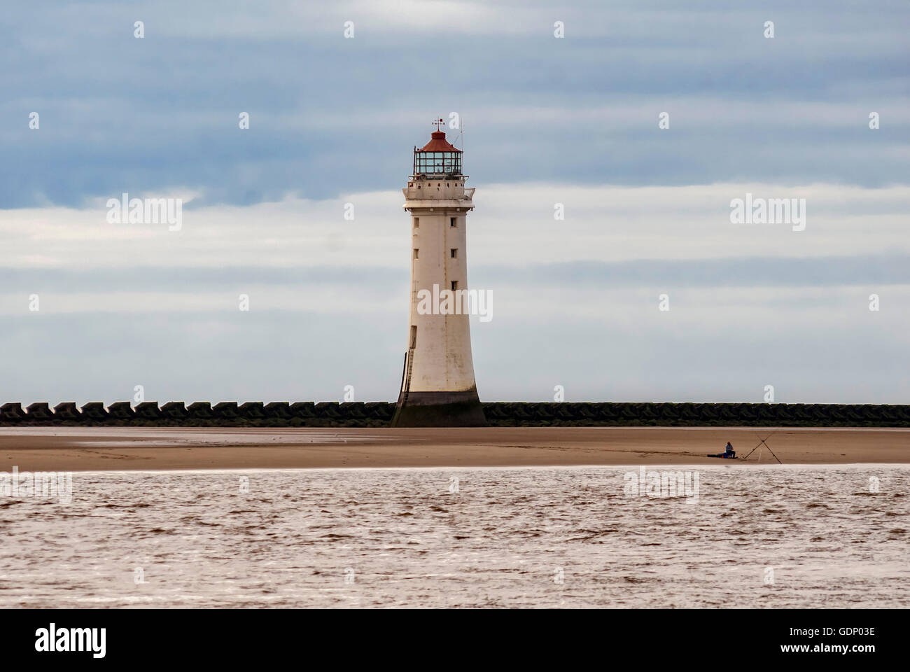 Lone angler fisherman fishing beach New Brighton Perch Rock lighthouse River Mersey. Merseyside North West England. Stock Photo