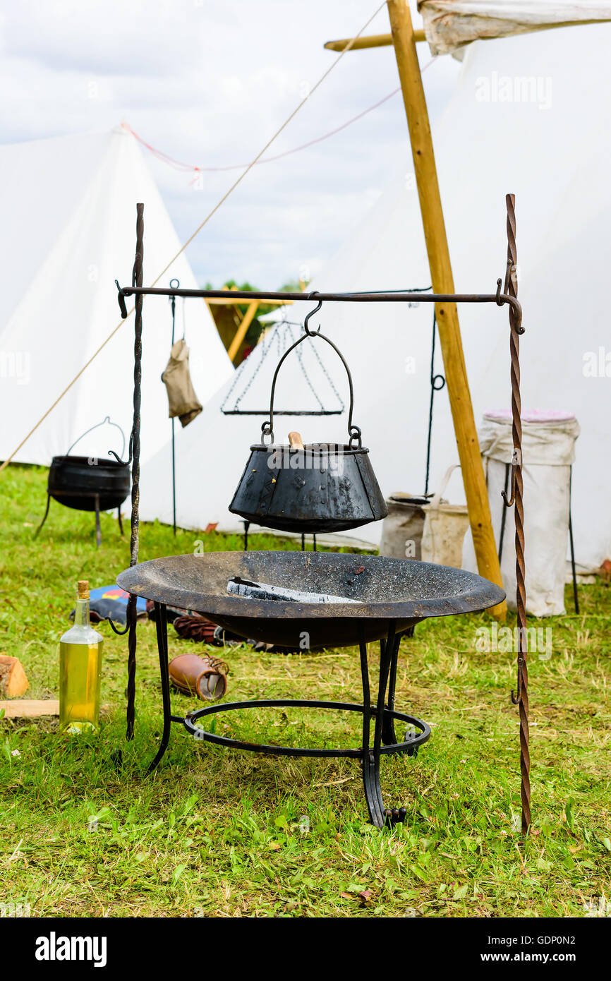 Outdoor cooking pot hanging over burnt wood and ashes. Pot is handmade