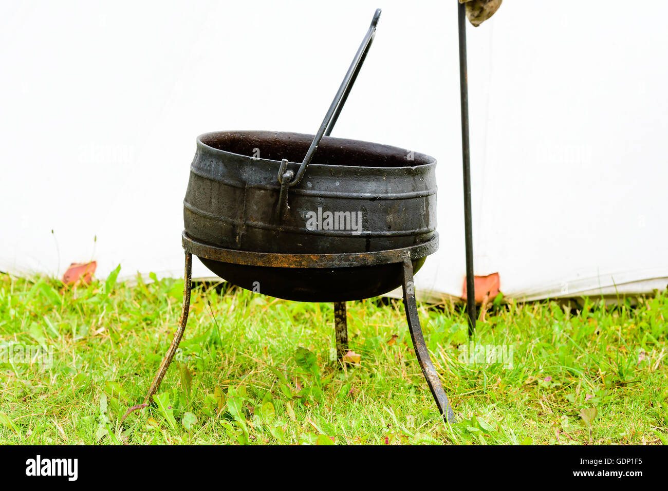 Outdoor iron cooking pot with handle. Cauldron is supported by metal