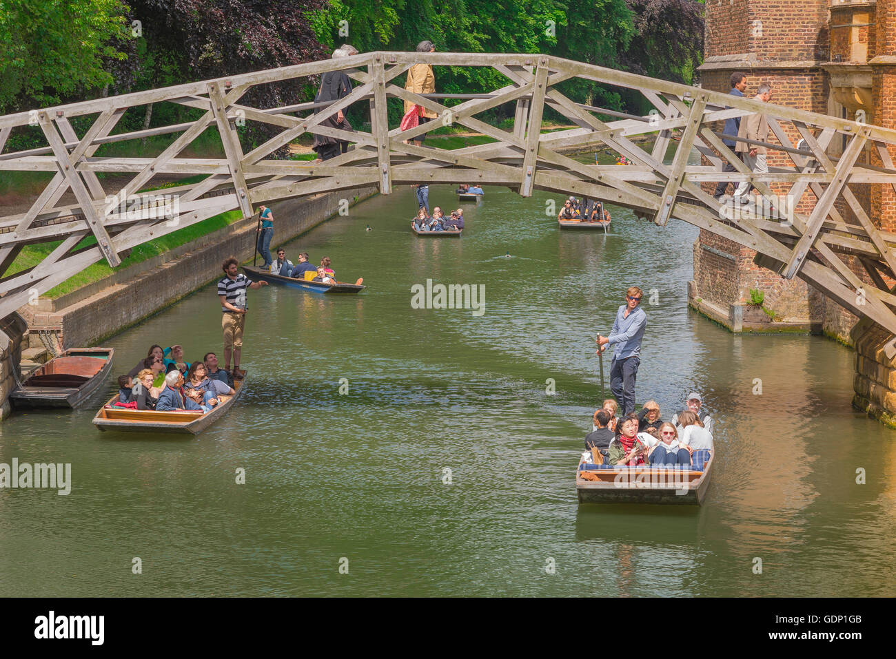 Punting Cambridge, tourists in punts glide under the famous wooden Mathematical Bridge in Cambridge, England. Stock Photo
