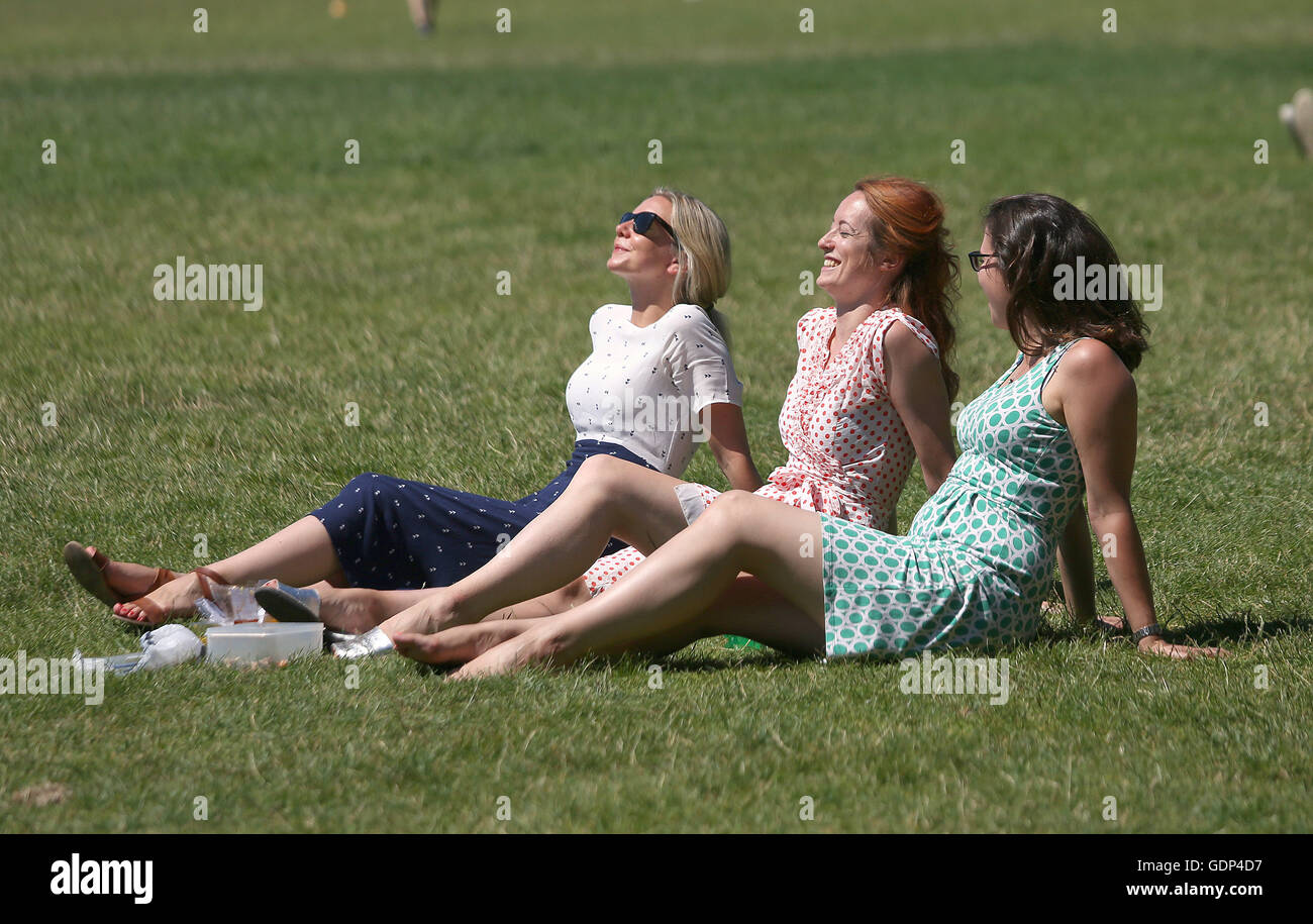 (Left to right) Becky Starr, Cesca Hall and Rachel de Minckwitz enjoy their lunch hour in Holland park, London, as Britain has sweltered on the hottest day of the year so far, with soaring temperatures sparking a surge in calls for medical help and causing delays on the railway. Stock Photo