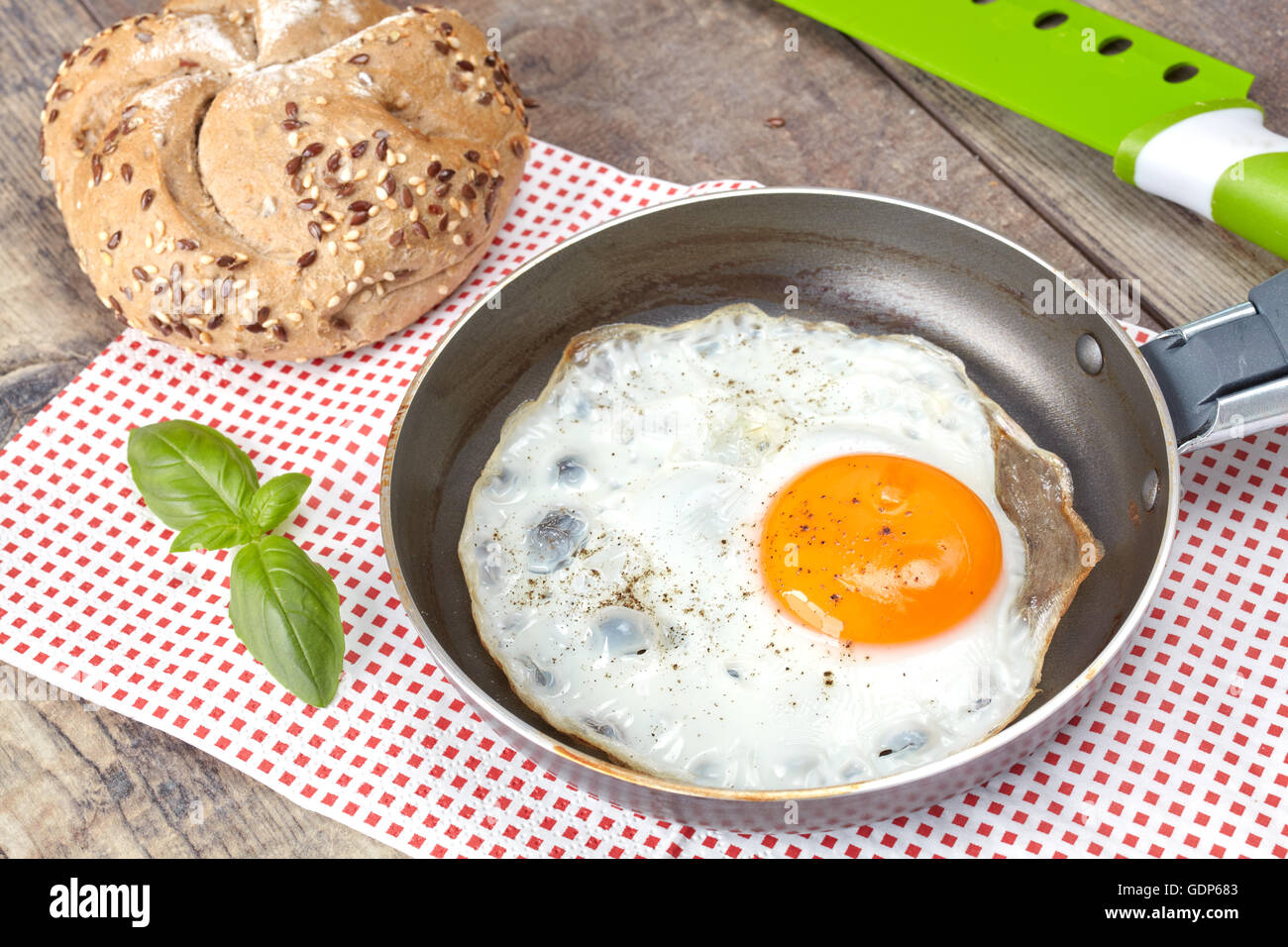 Fried egg in a pan with full grain roll. Stock Photo