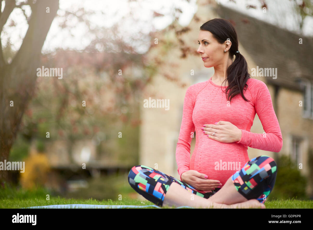 Pregnant woman sitting outdoors, holding belly Stock Photo - Alamy