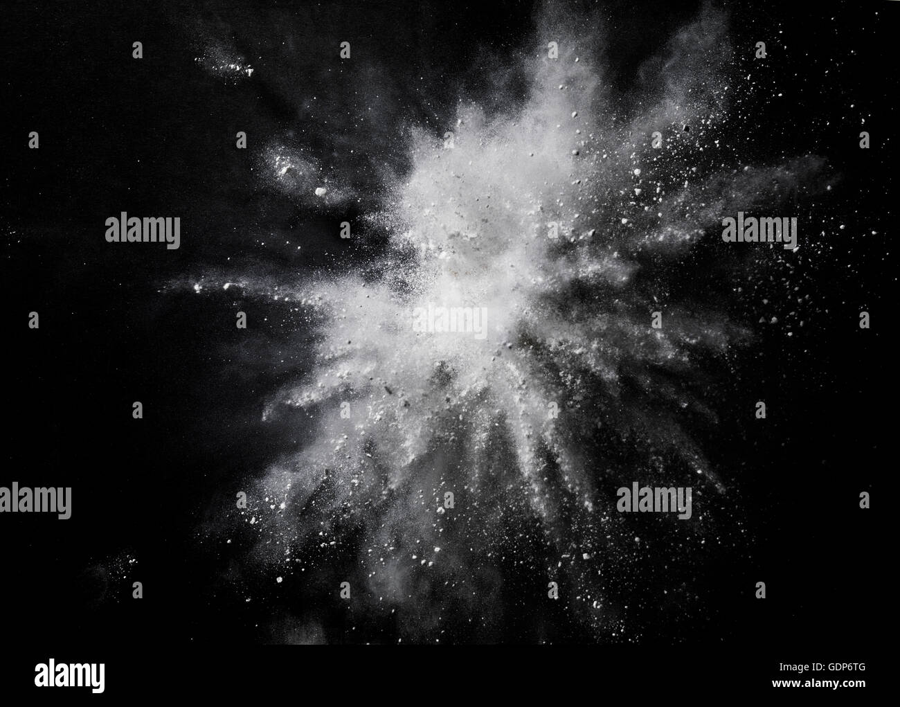 White dust exploding mid air against black background Stock Photo