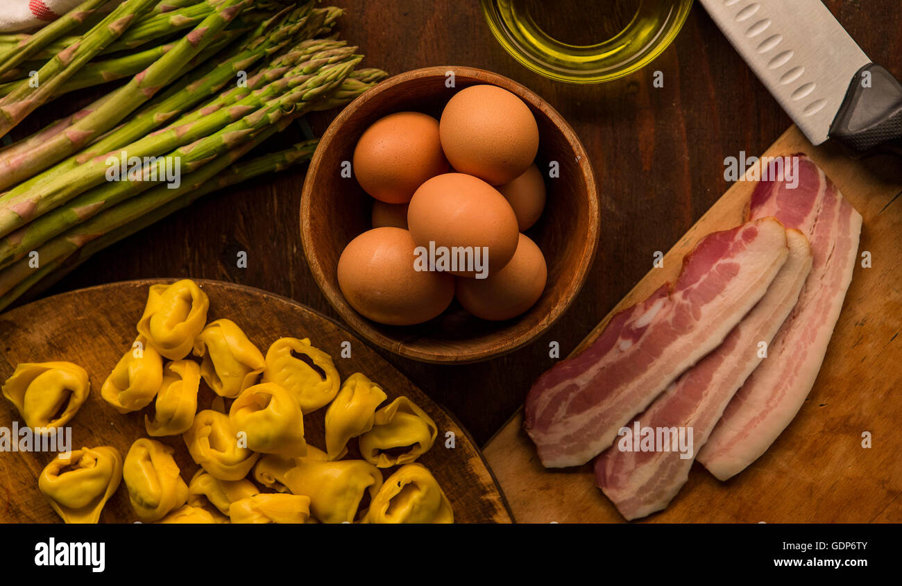 Overhead view of raw and prepared food, pasta, eggs and asparagus Stock Photo