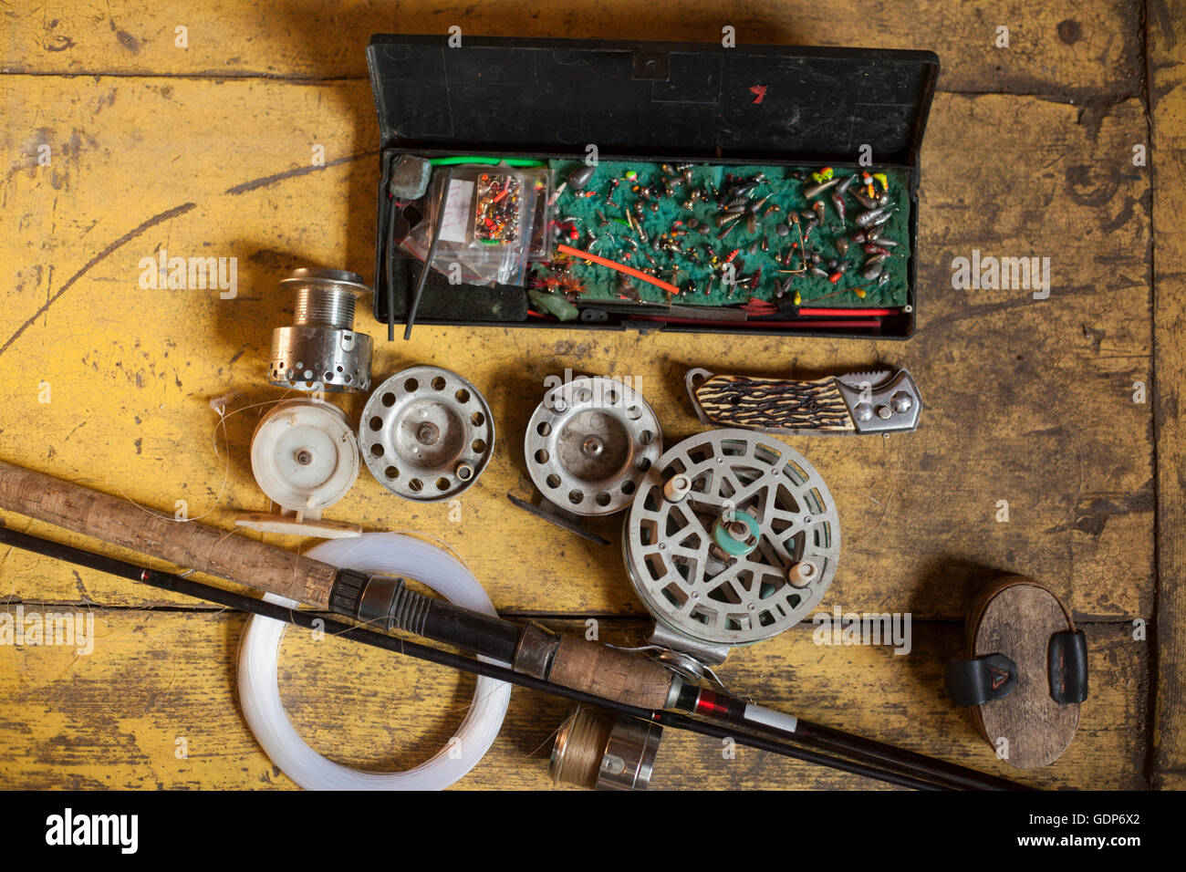 Overhead view of fishing rod and equipment on yellow shed floor Stock Photo