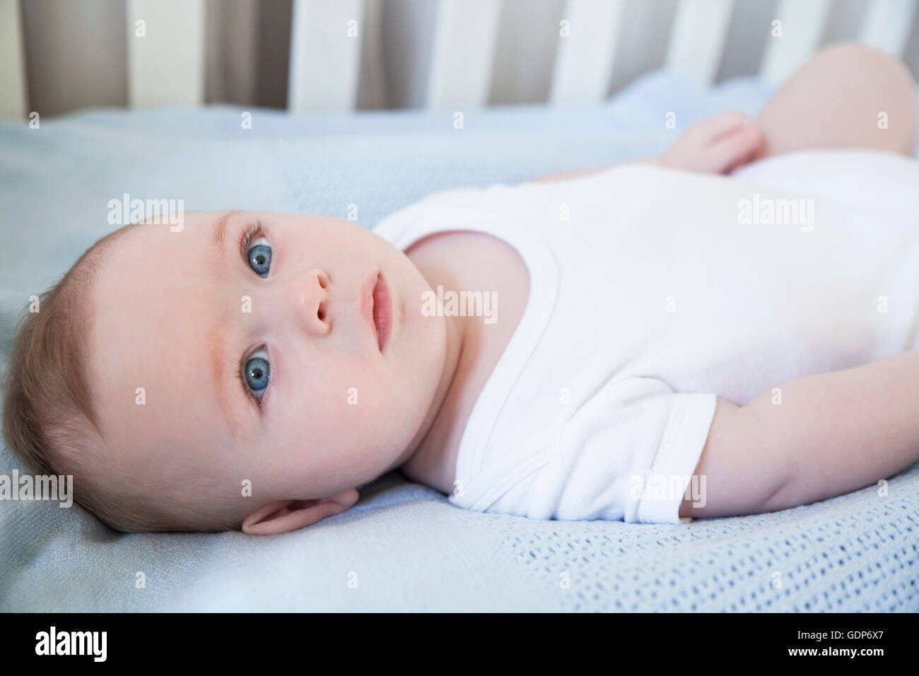 Blue eyed baby boy lying in his crib Stock Photo