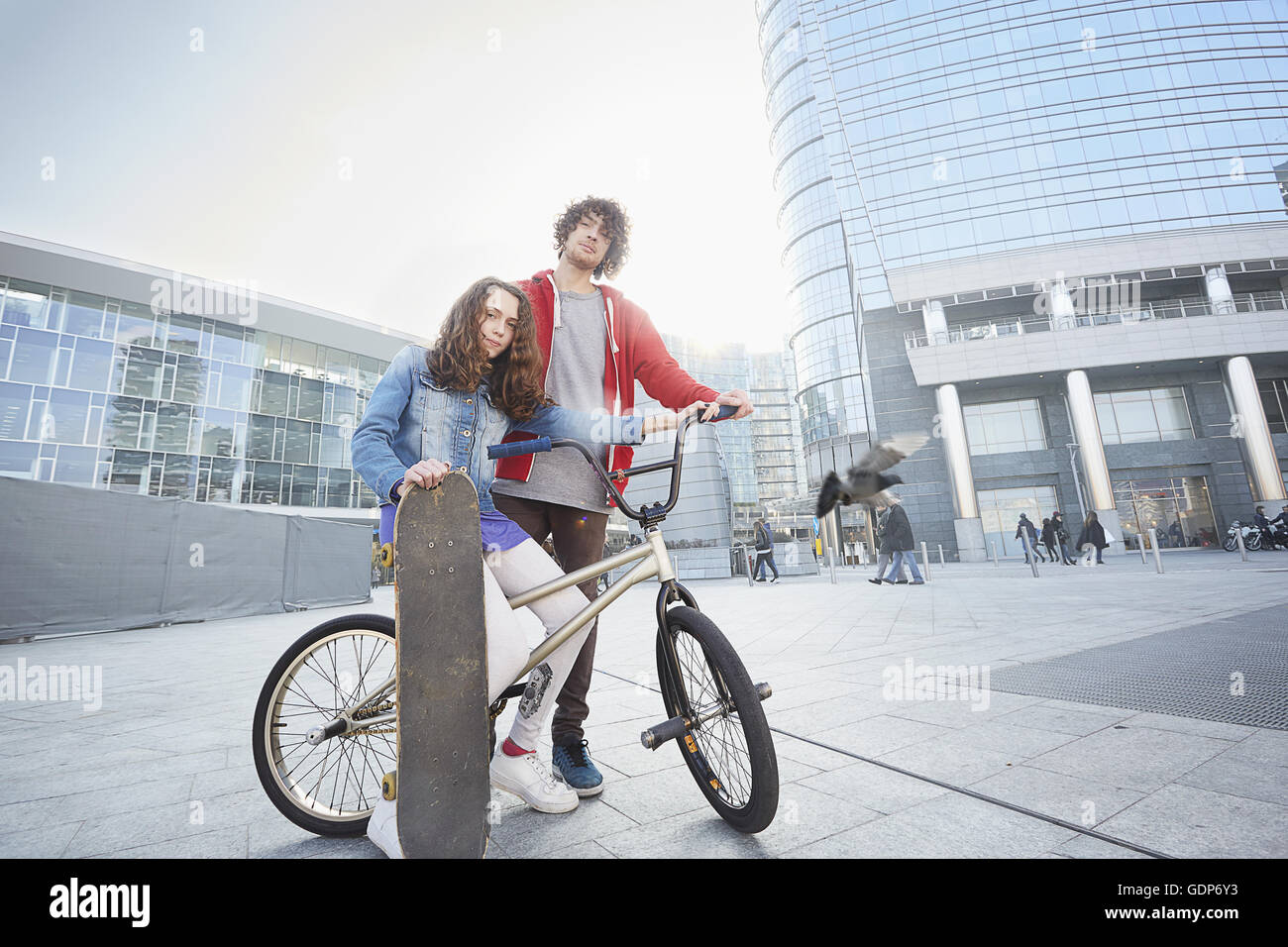 Girl and man with BMX and skateboard in urban area Stock Photo