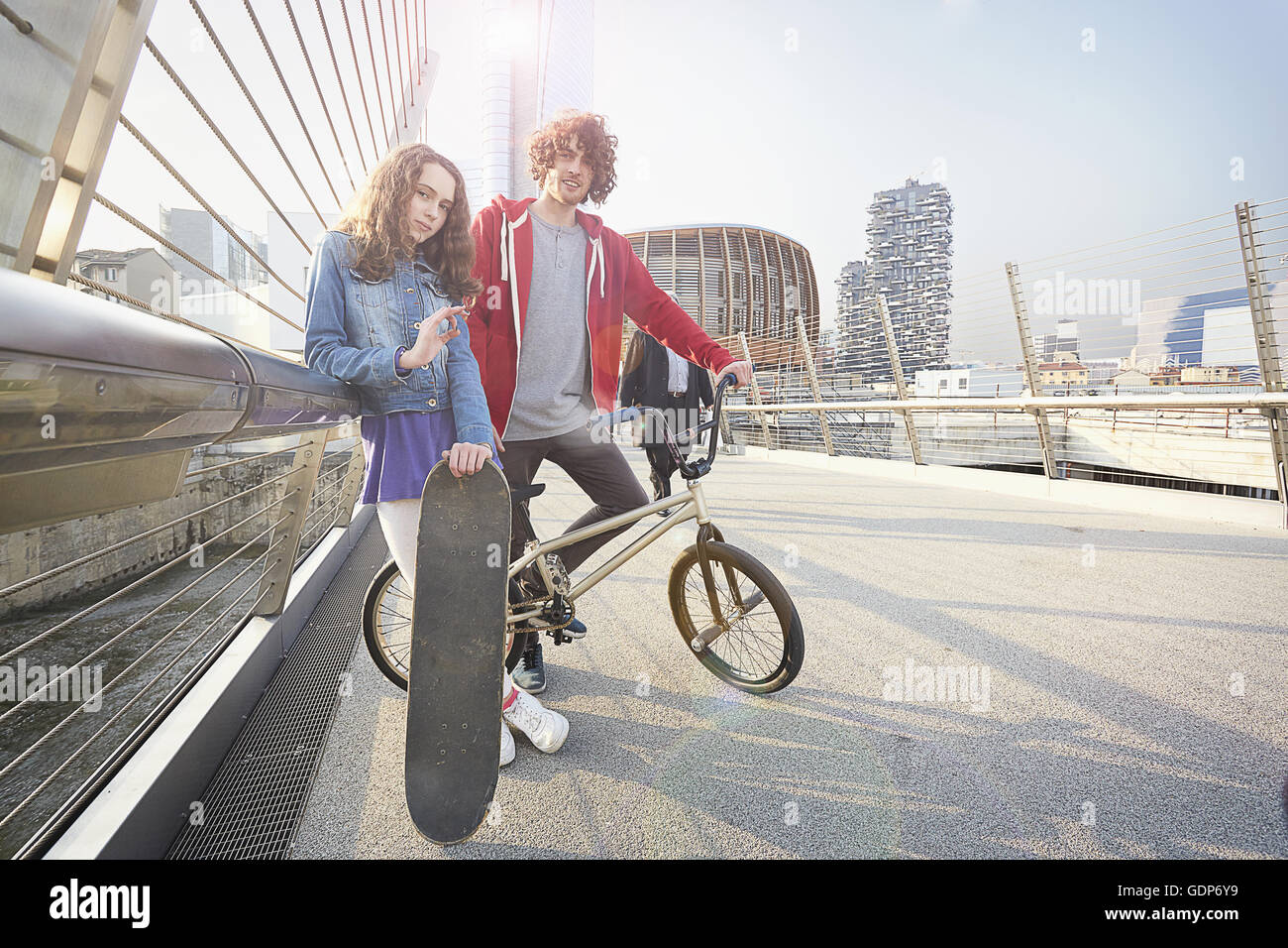 Girl and man with BMX and skateboard in urban area Stock Photo