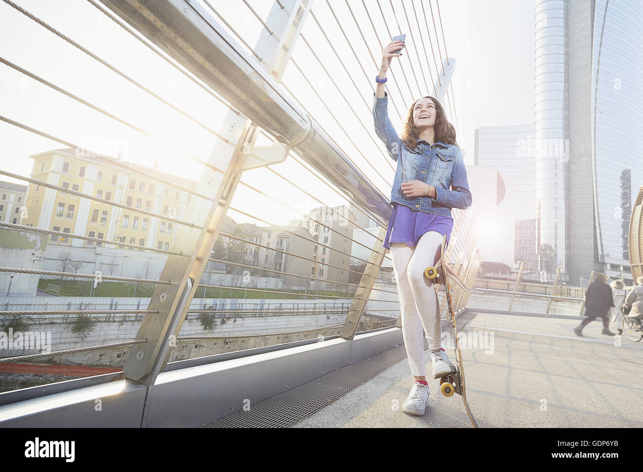 Girl with skateboard using smartphone to take selfie Stock Photo