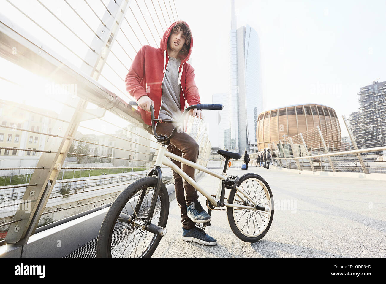 Man with BMX leaning against hand rail in urban area Stock Photo