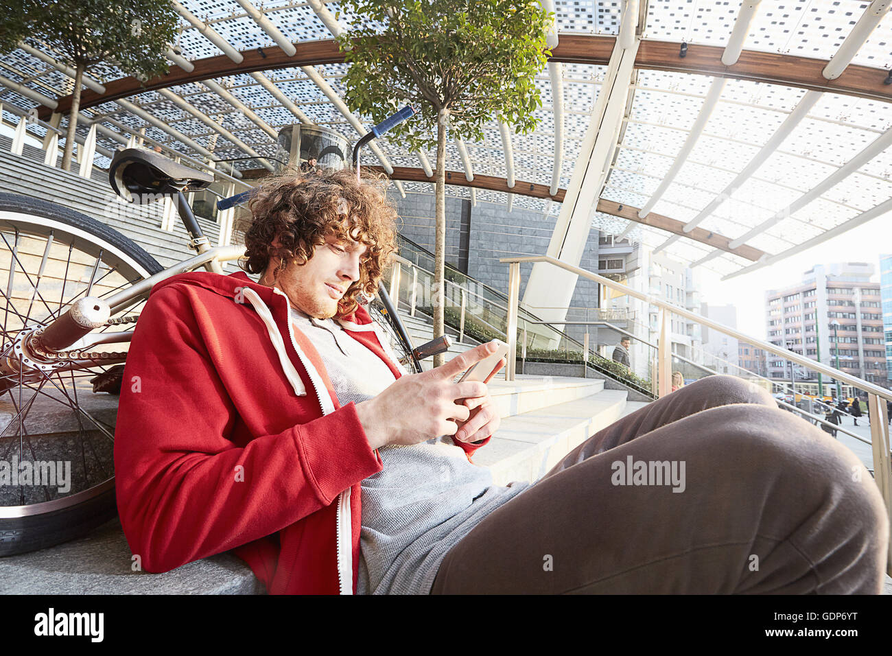 Man sitting on steps with BMX using smartphone Stock Photo