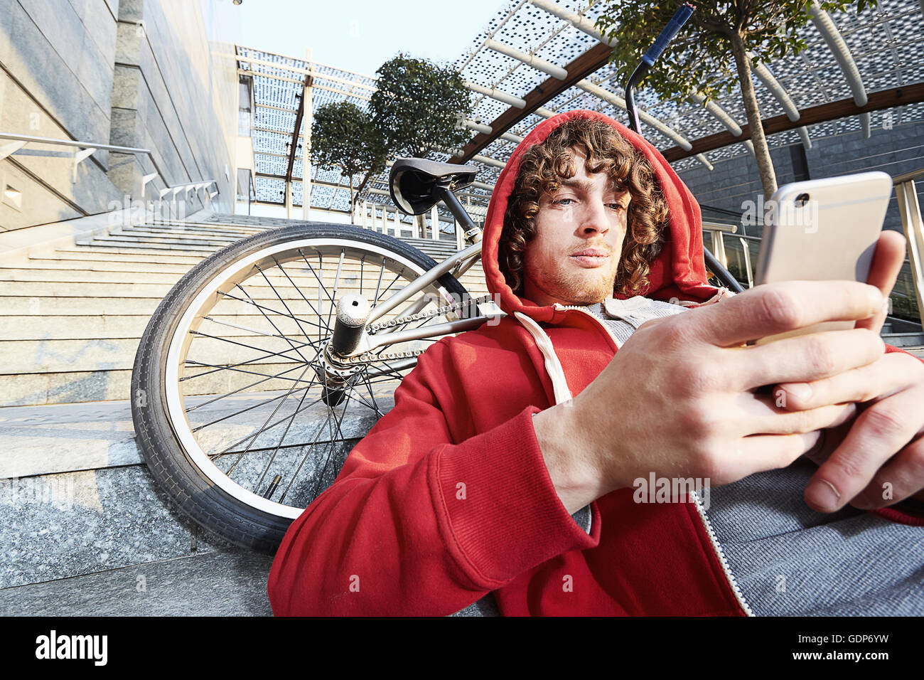 Man sitting on steps with BMX using smartphone Stock Photo