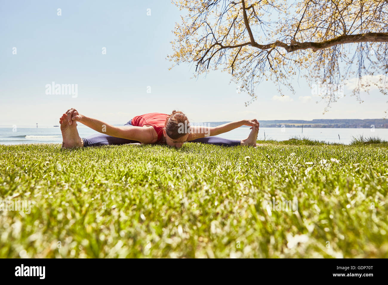 Woman bending forward in yoga position, touching toes Stock Photo