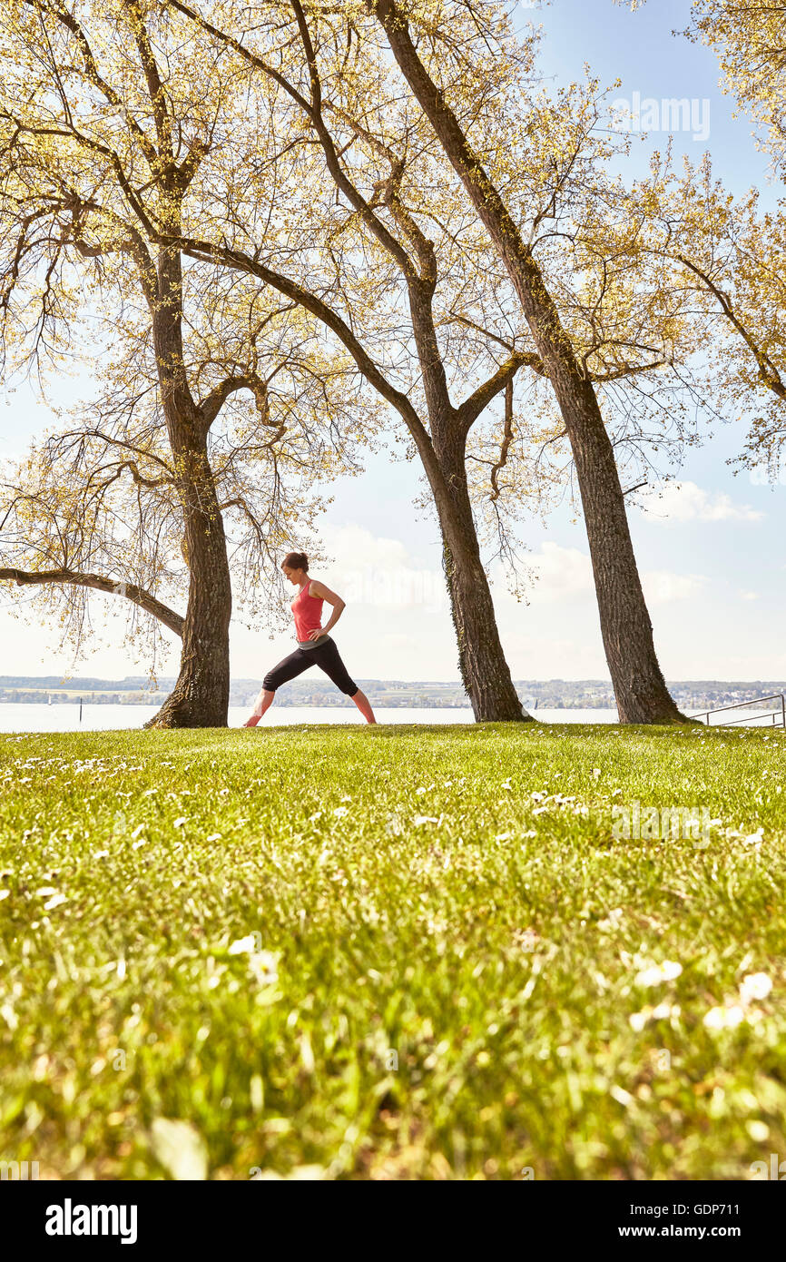 Side view of woman practising yoga by lake Stock Photo