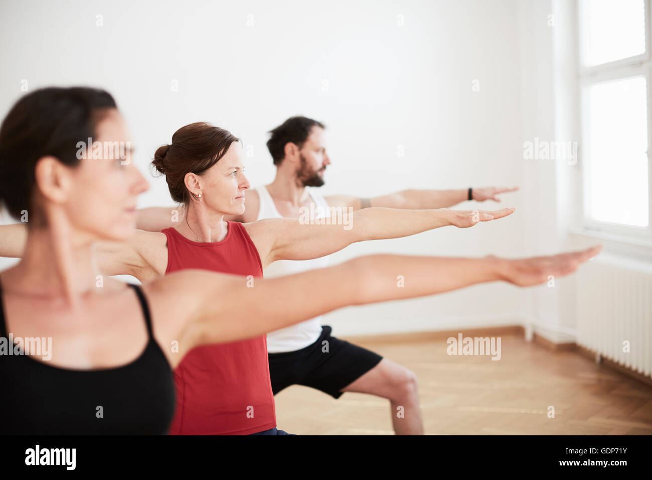 People in exercise studio arms open in yoga position Stock Photo