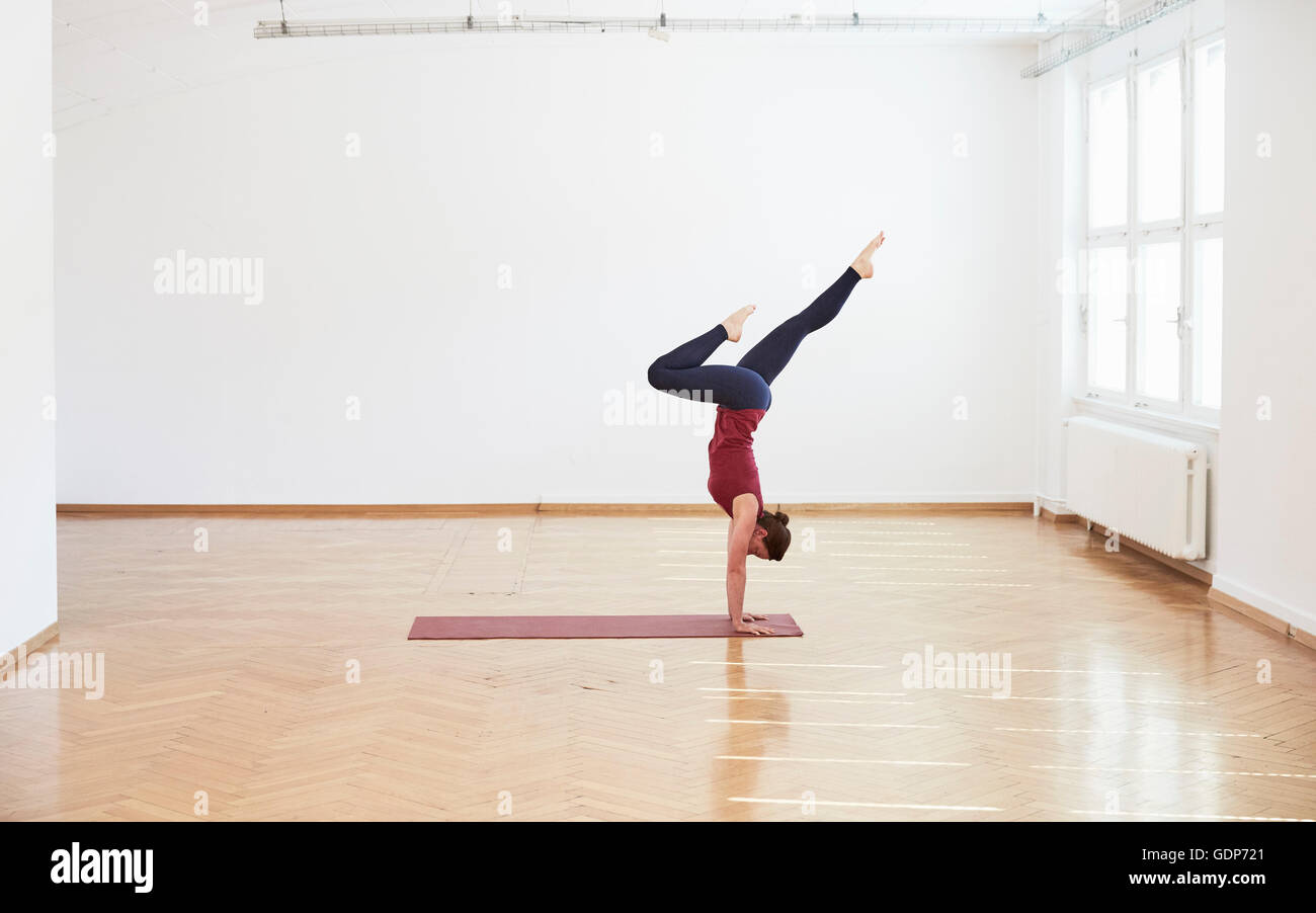 Side view of woman in exercise studio doing handstand Stock Photo