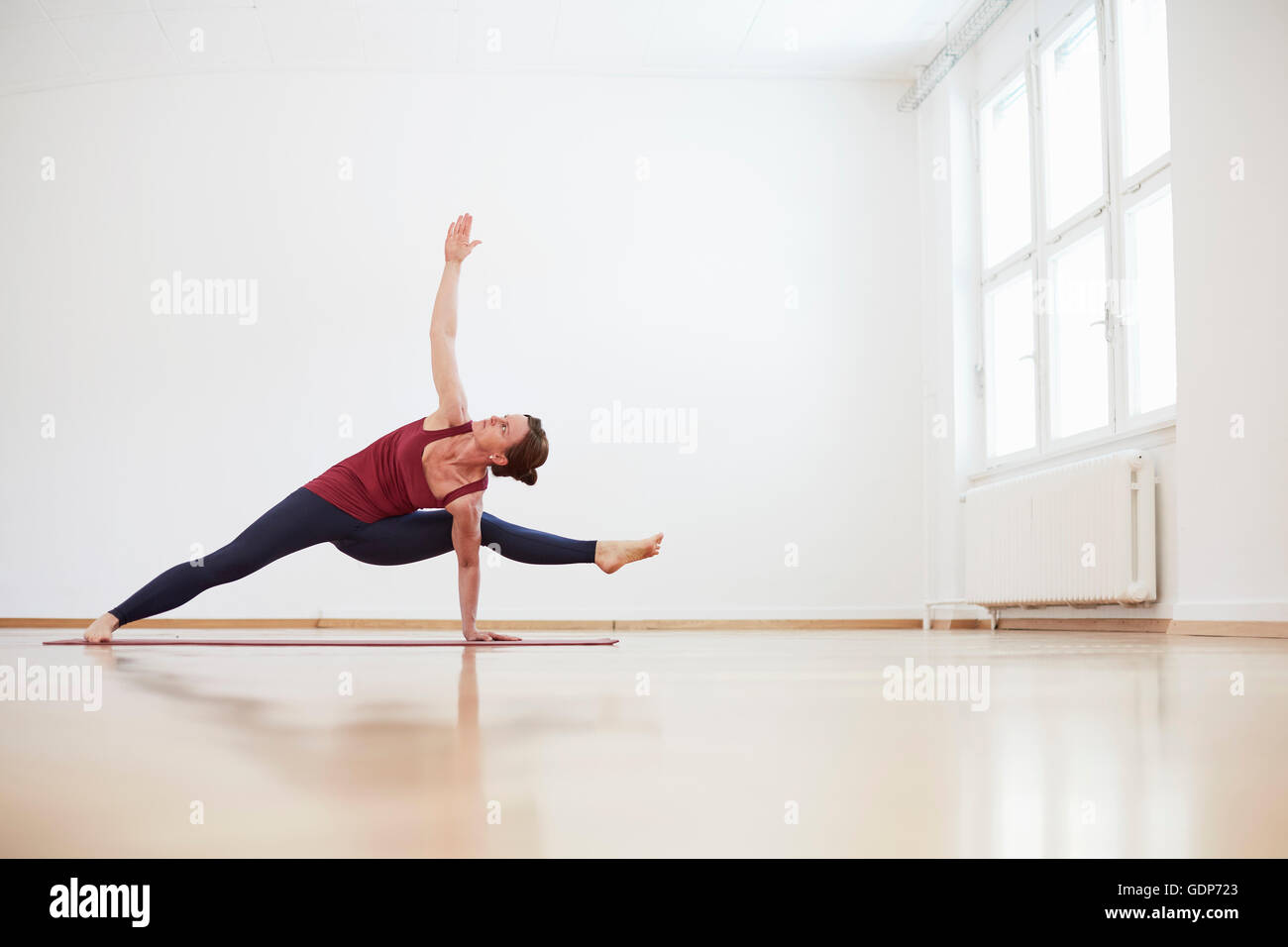 Woman in exercise studio arm and leg raised in yoga position Stock Photo