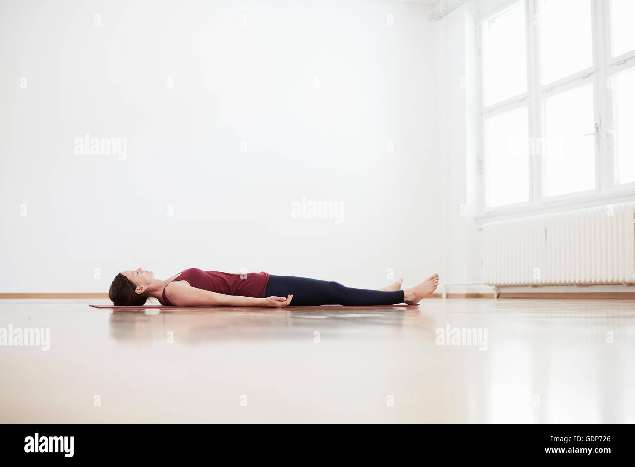 Woman in exercise studio lying on back on floor Stock Photo