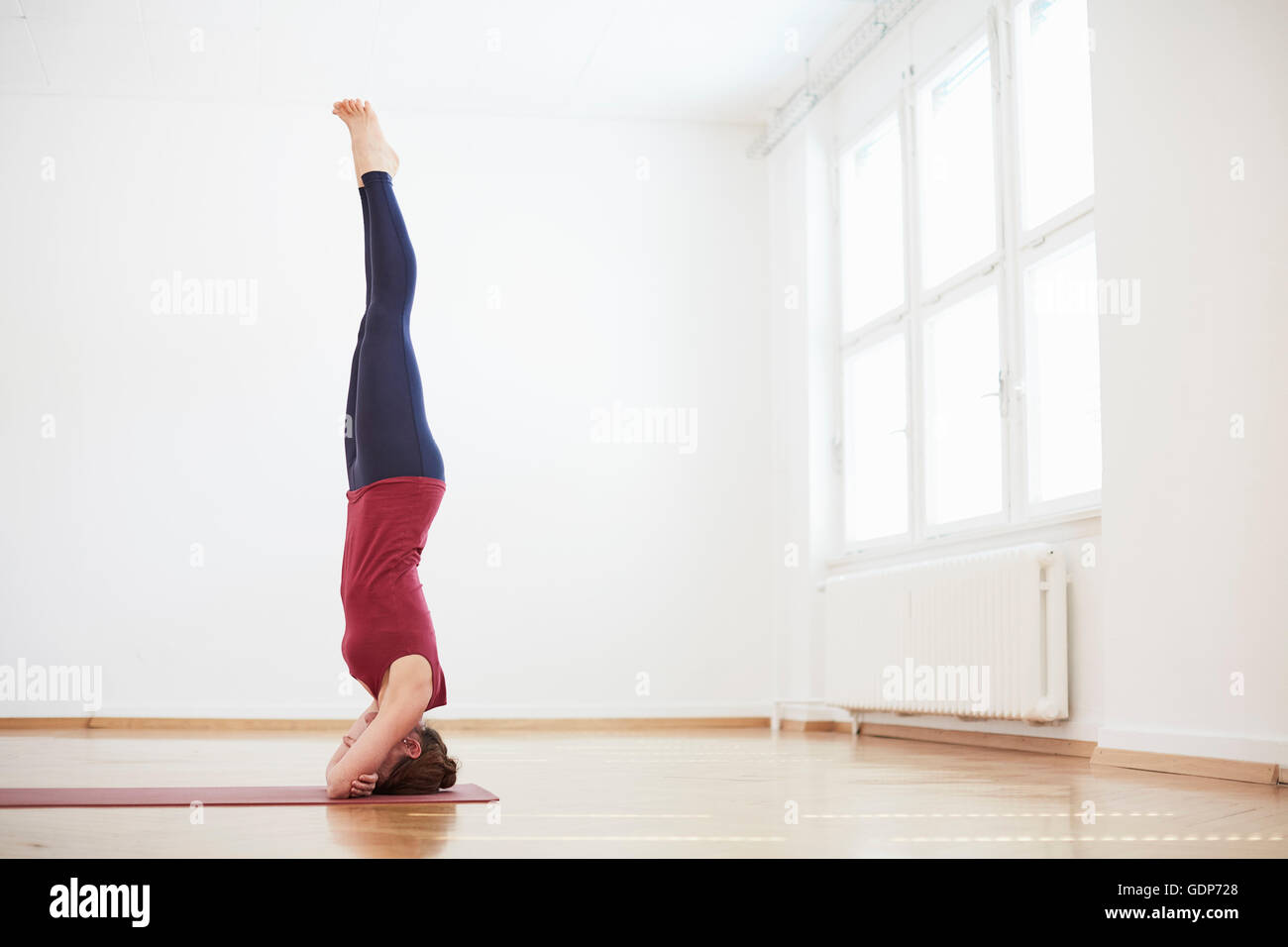 Woman in exercise studio doing headstand Stock Photo