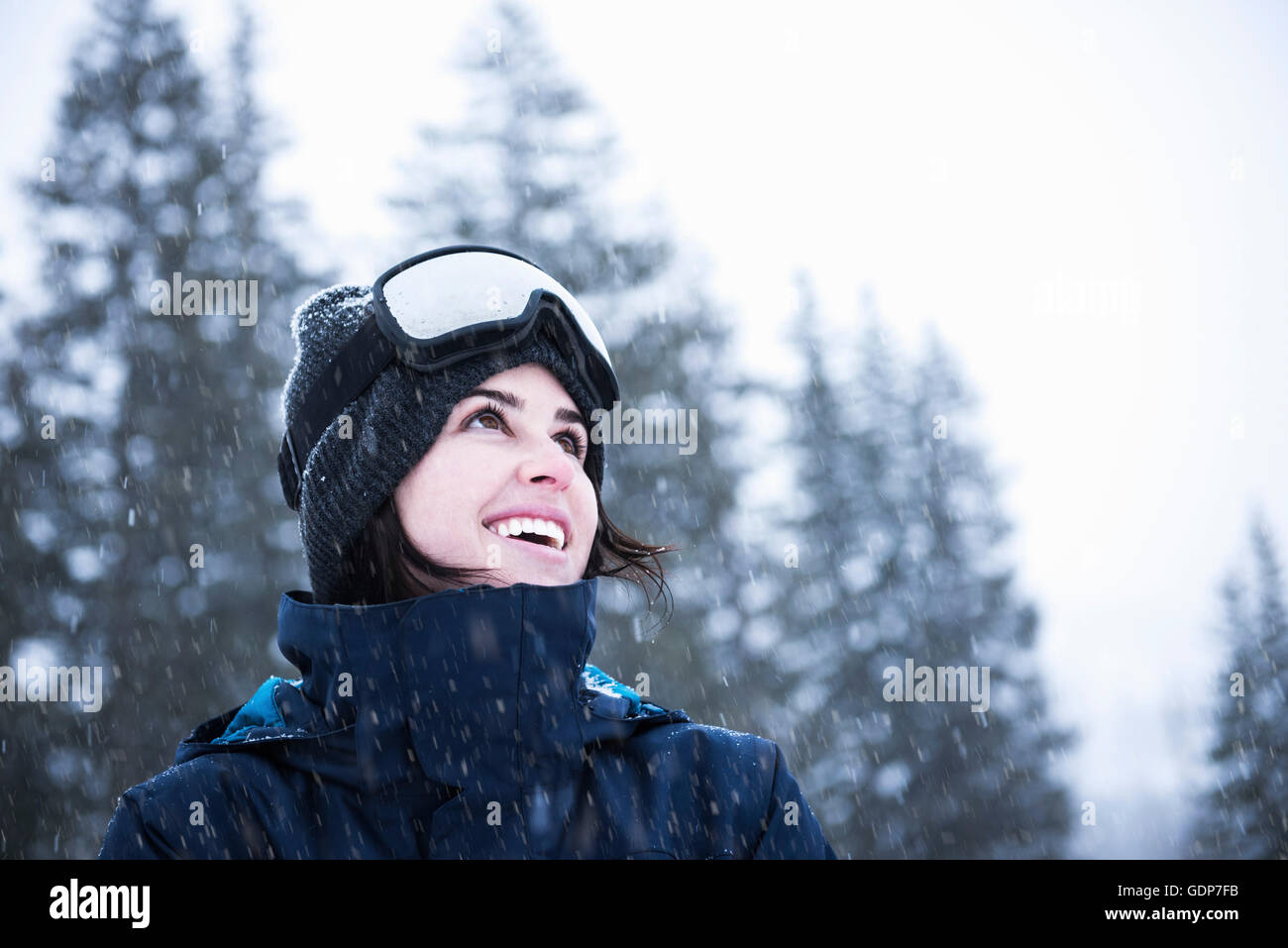Portrait of young woman wearing ski goggles looking up at snow, Brighton Ski Resort outside of Salt Lake City, Utah, USA Stock Photo