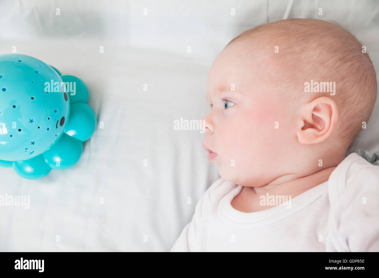 Baby boy staring at blue baby toy, overhead view Stock Photo