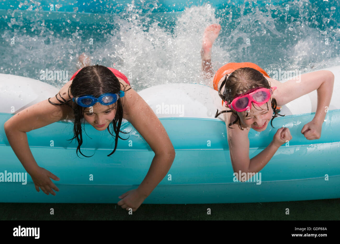 Two girls lying on front splashing water in paddling pool Stock Photo Alamy