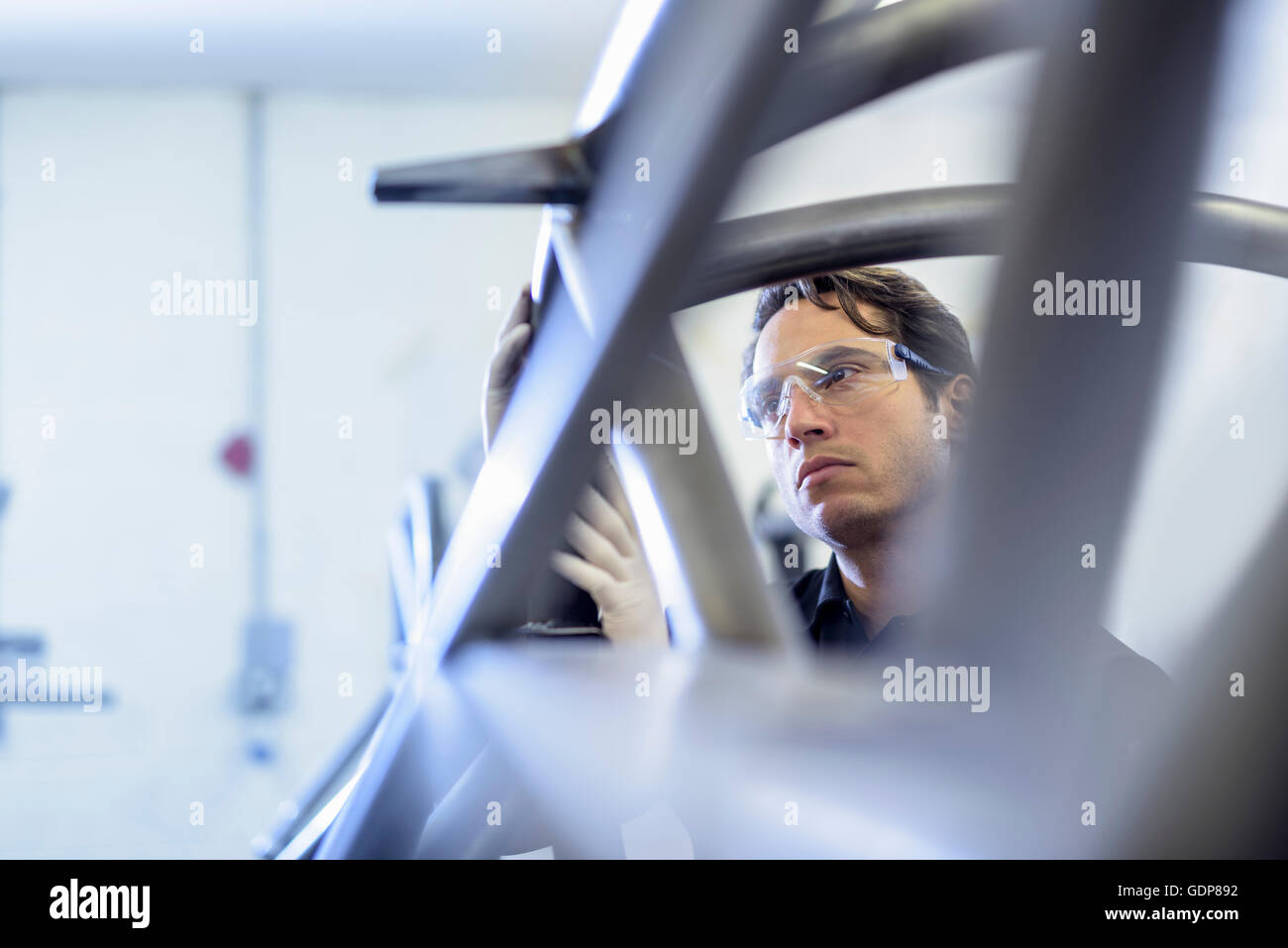 Engineer inspecting racing car roll cage in racing car factory Stock Photo