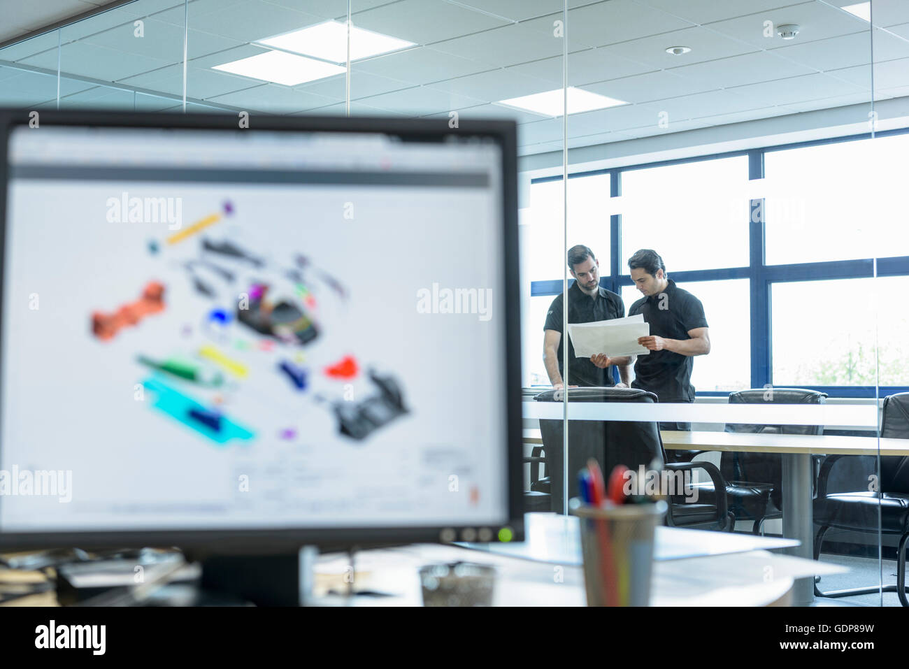 Engineers work with CAD design imagery in racing car factory Stock Photo