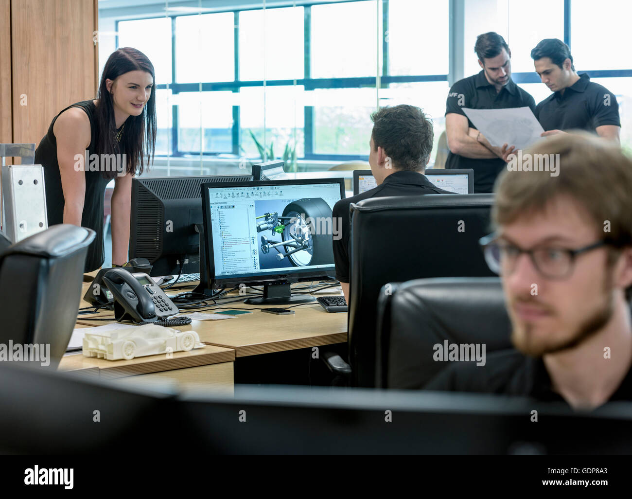 Engineers work with CAD design imagery in racing car factory Stock Photo