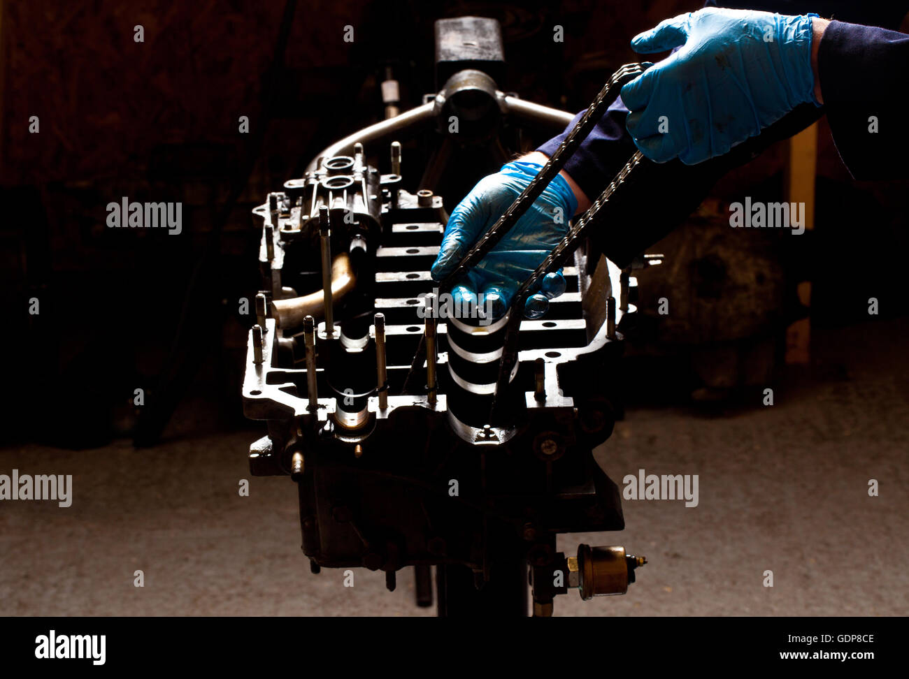 Male mechanic repairing car engine, holding cam chain Stock Photo