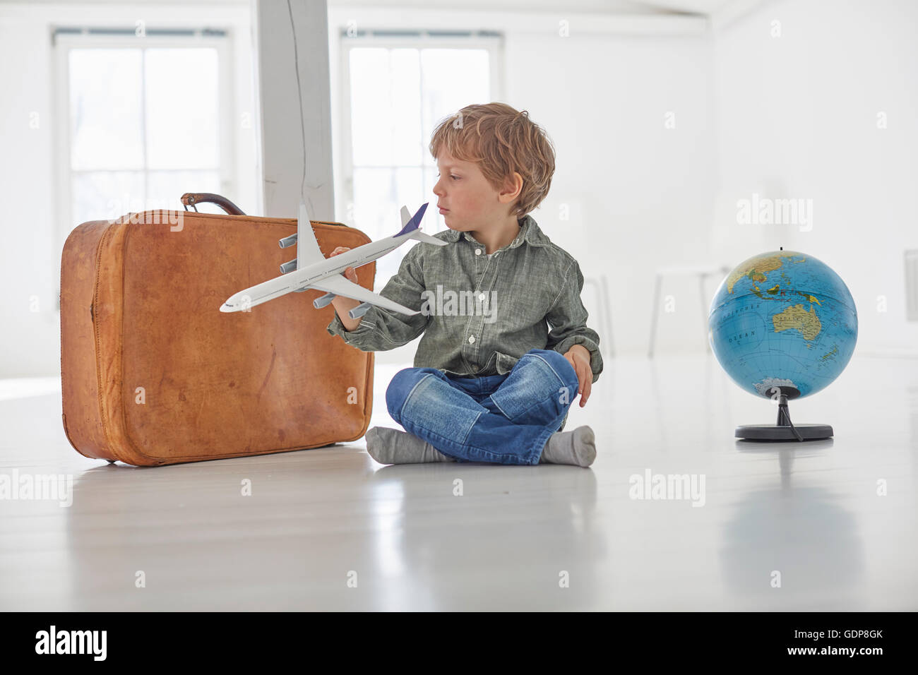 Boy sitting on floor playing with toy airplane Stock Photo