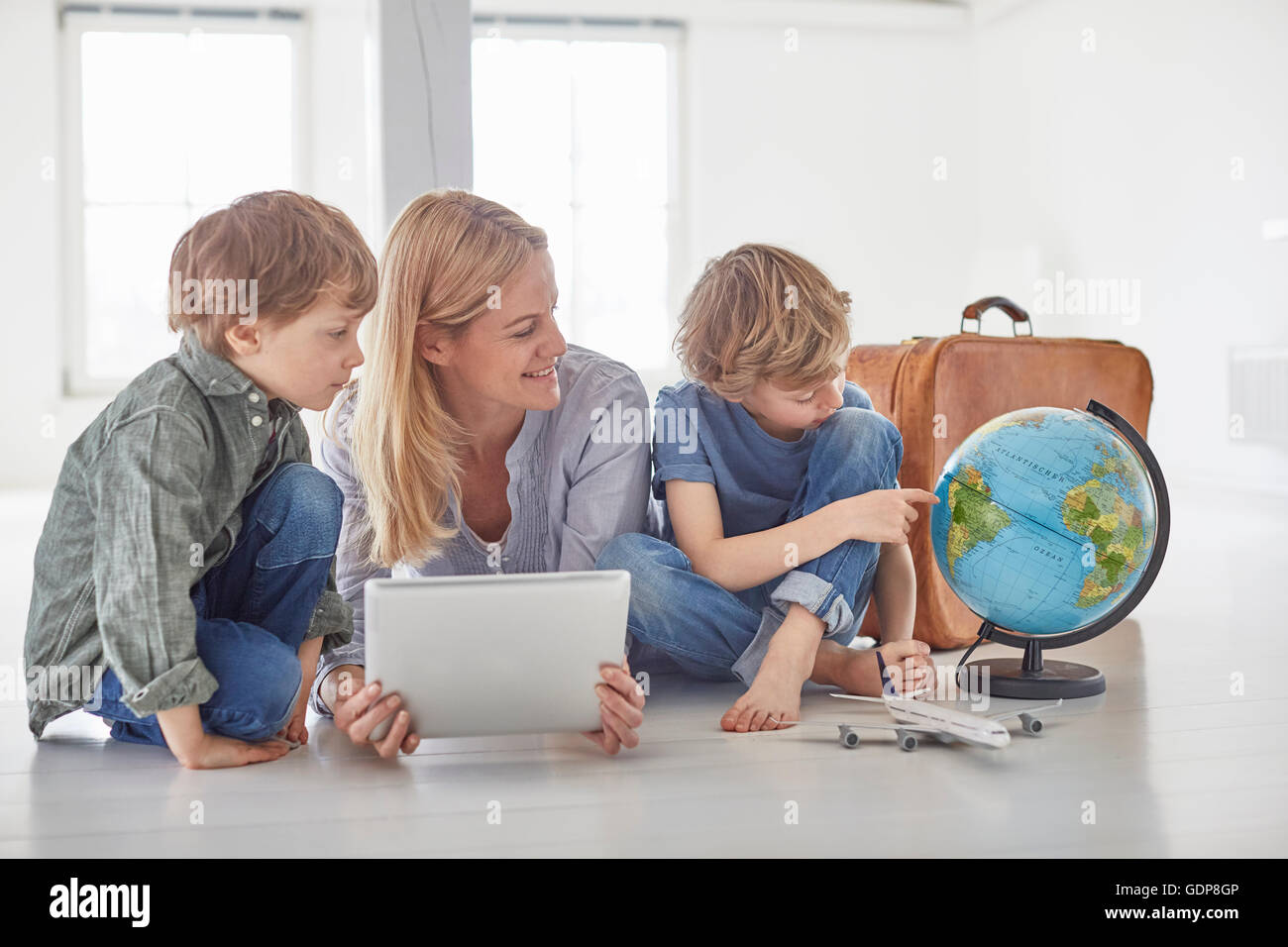 Mature woman and two son's sitting on floor looking at globe Stock Photo