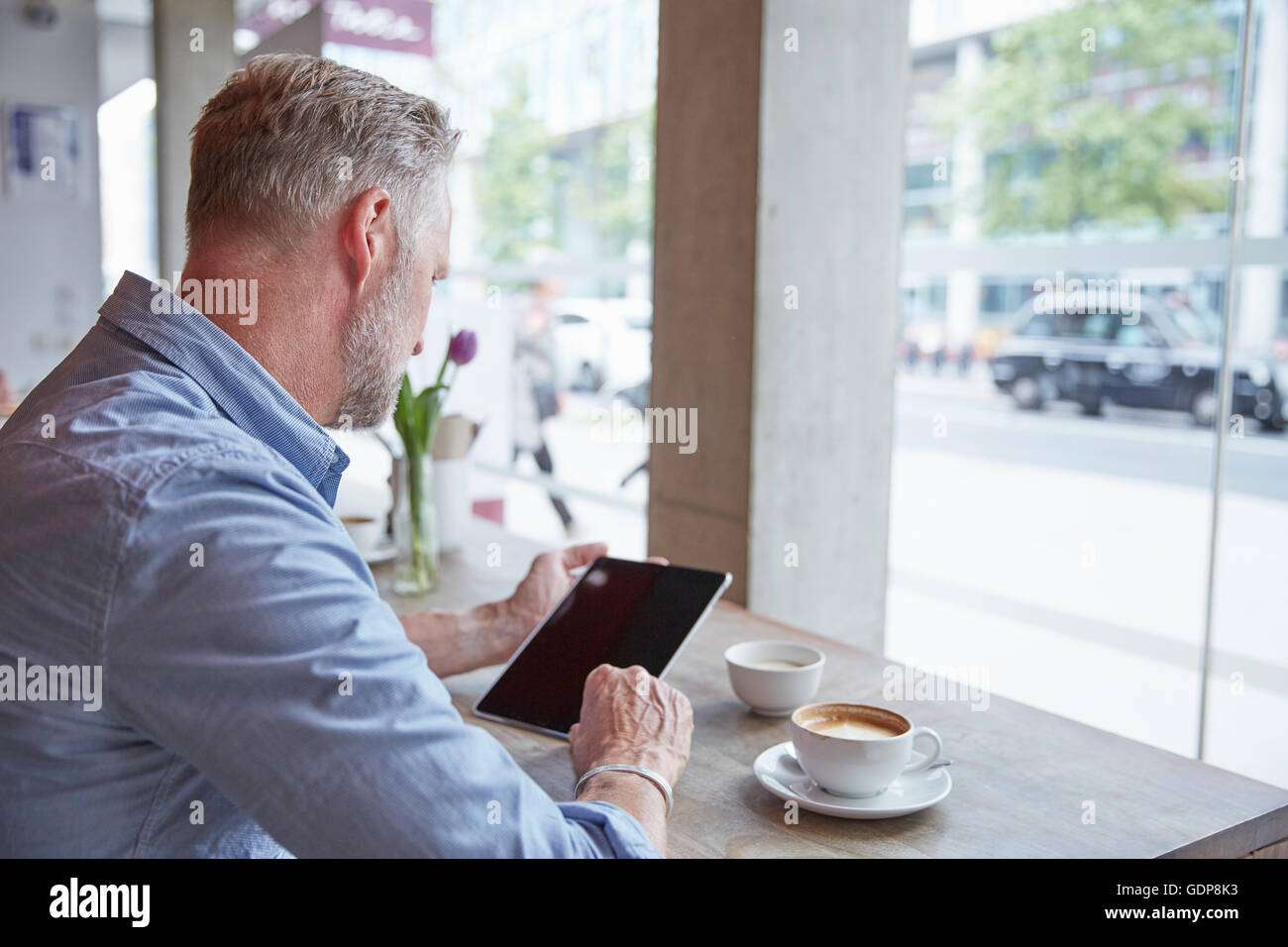 Mature man sitting in cafe, using digital tablet, rear view Stock Photo