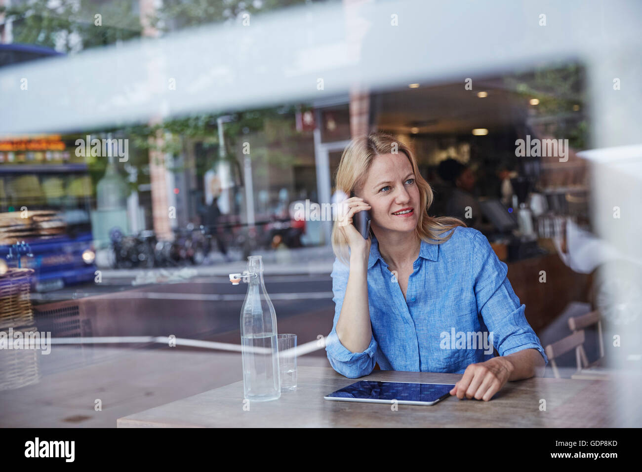 Mature woman sitting in cafe, using smartphone Stock Photo