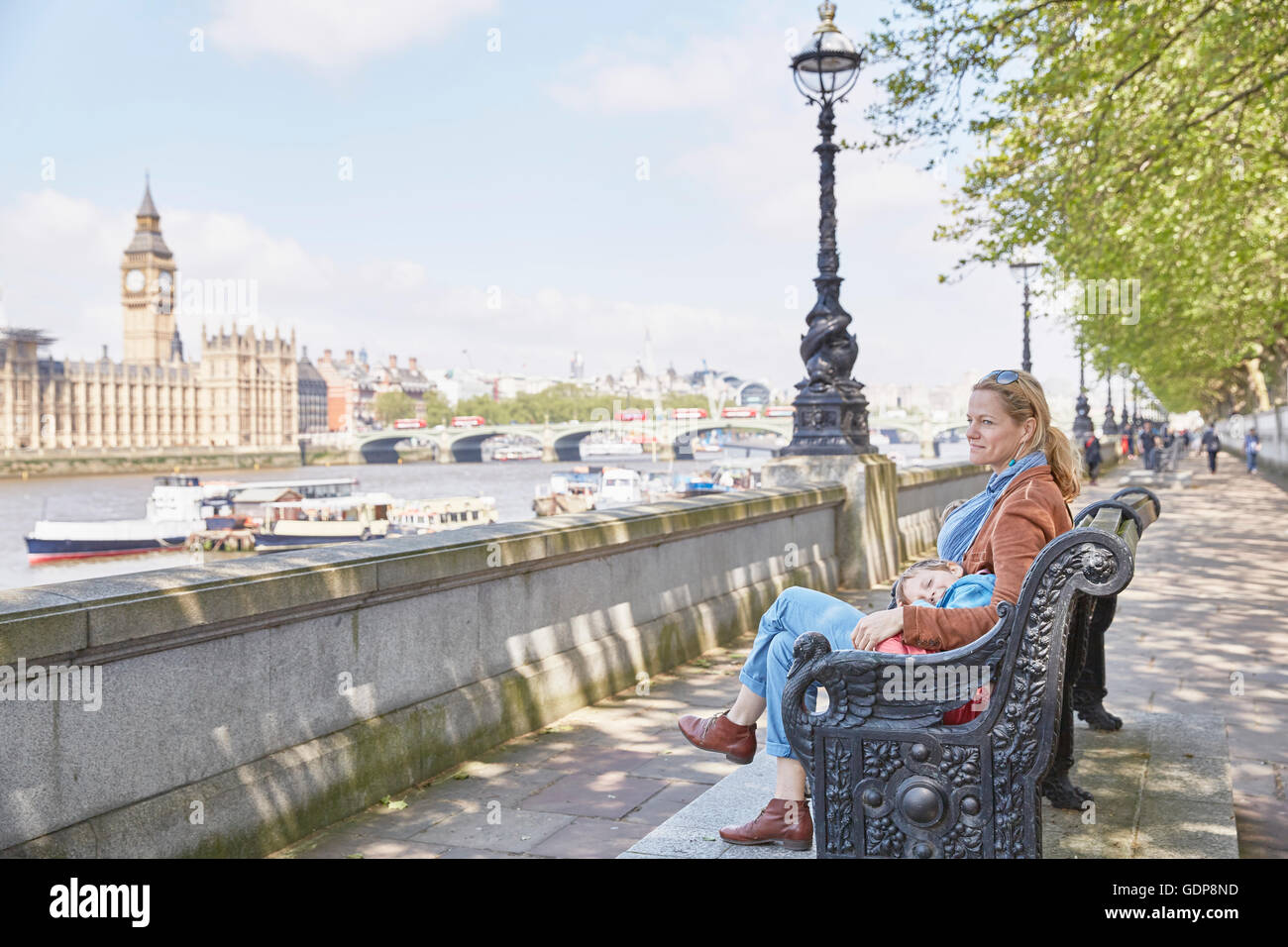 Mother and son resting on bench by river thames Stock Photo