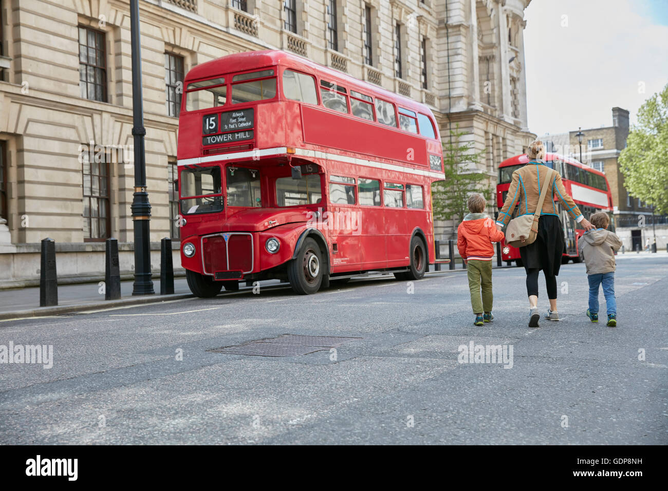 Rear view of mother and sons looking at red double decker bus Stock Photo
