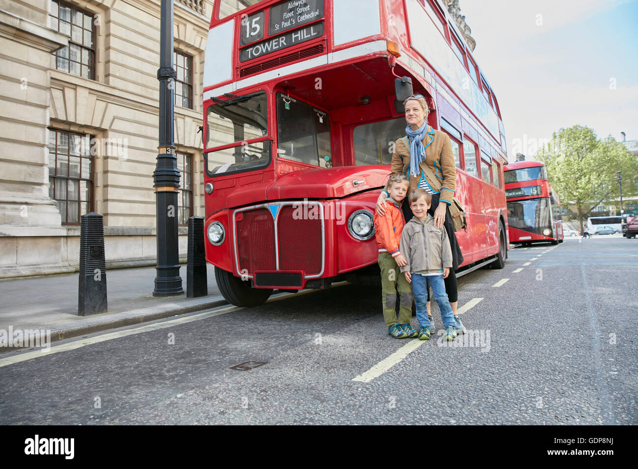 Mother and sons in front of red double decker bus Stock Photo