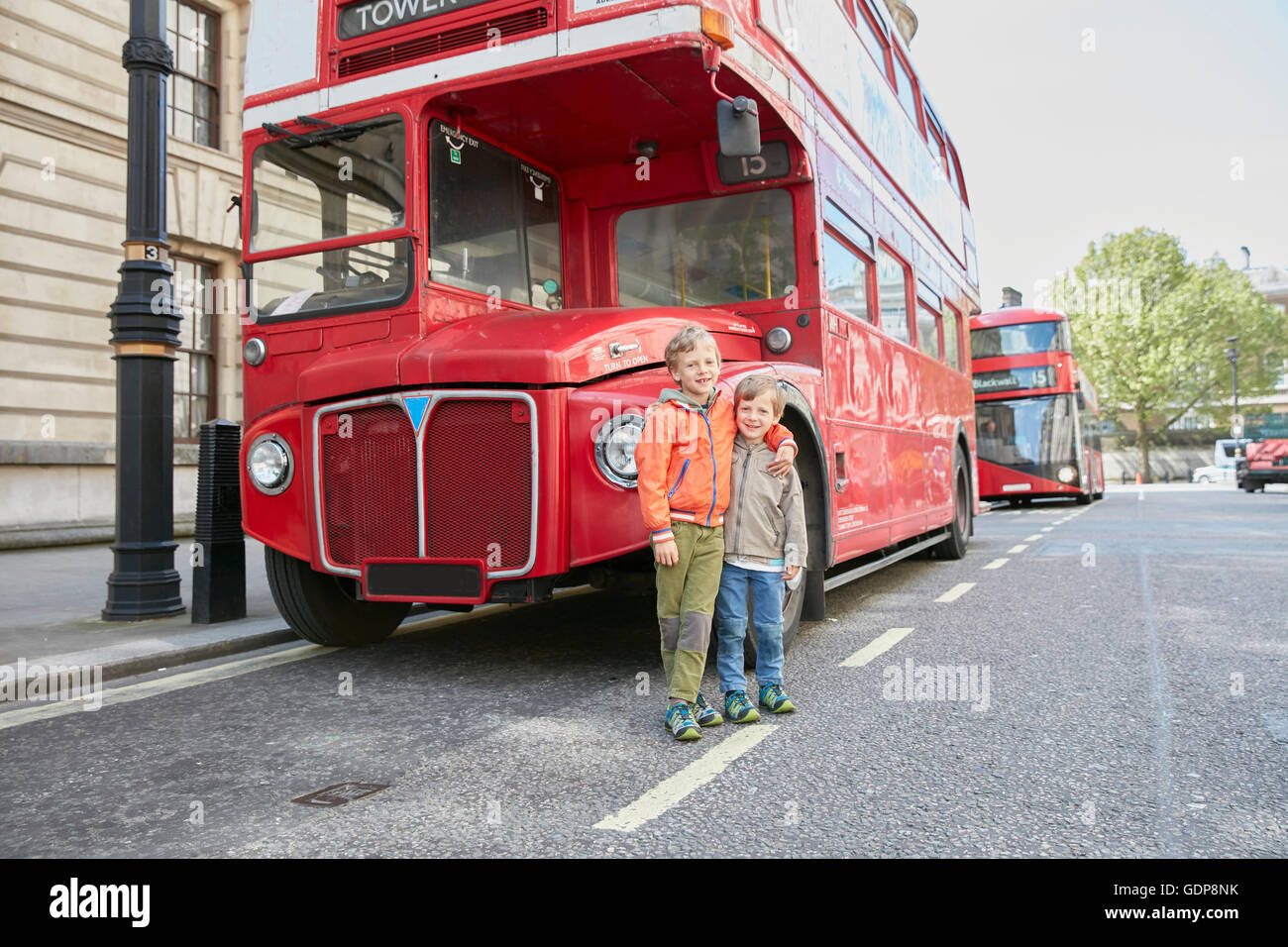 Boys in front of red double decker bus Stock Photo