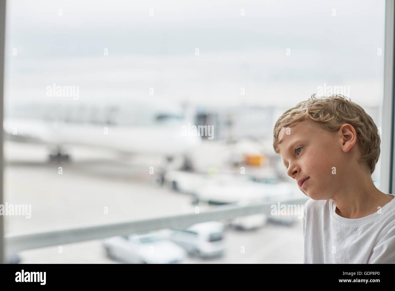 Boy looking out of airport window Stock Photo
