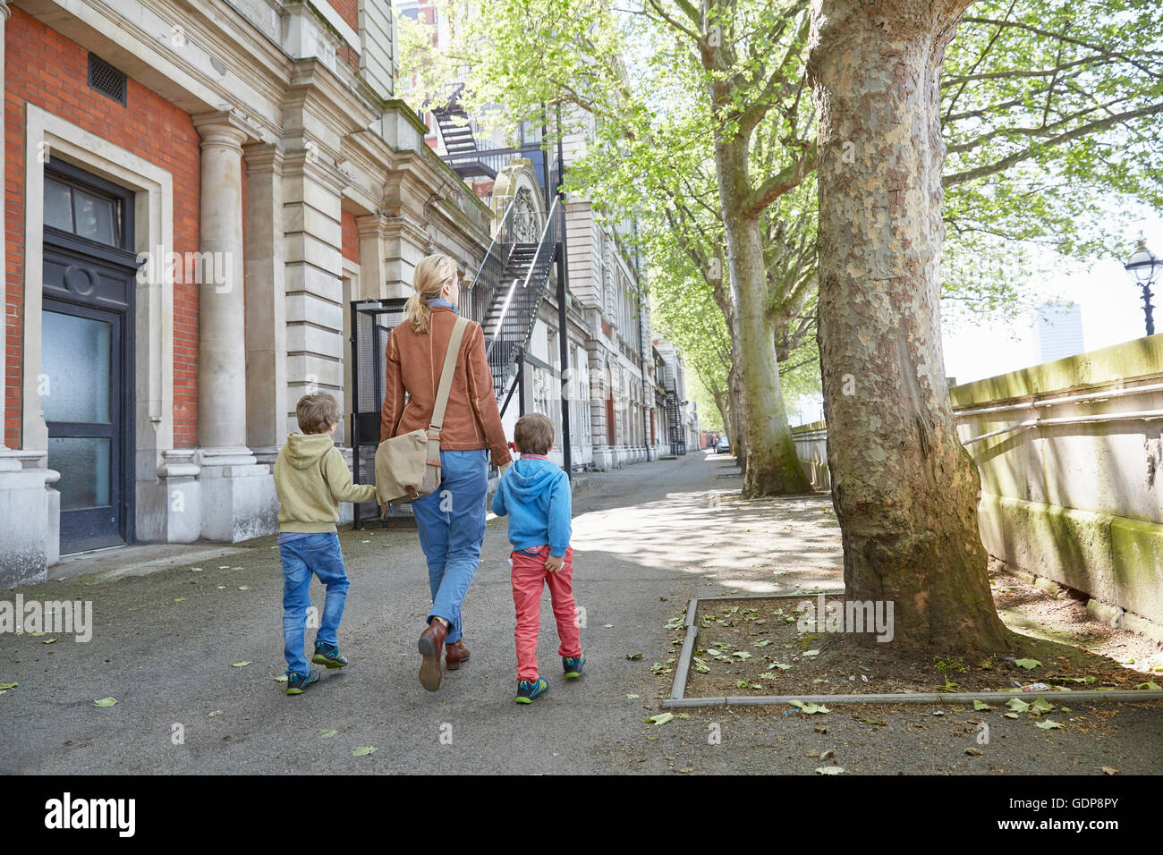 Rear view of mother and sons holding hands in street Stock Photo