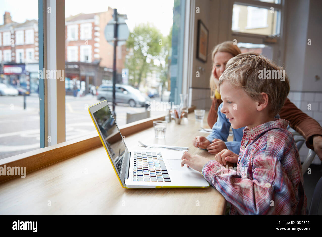 Mother and son at window seat in cafe using laptop Stock Photo