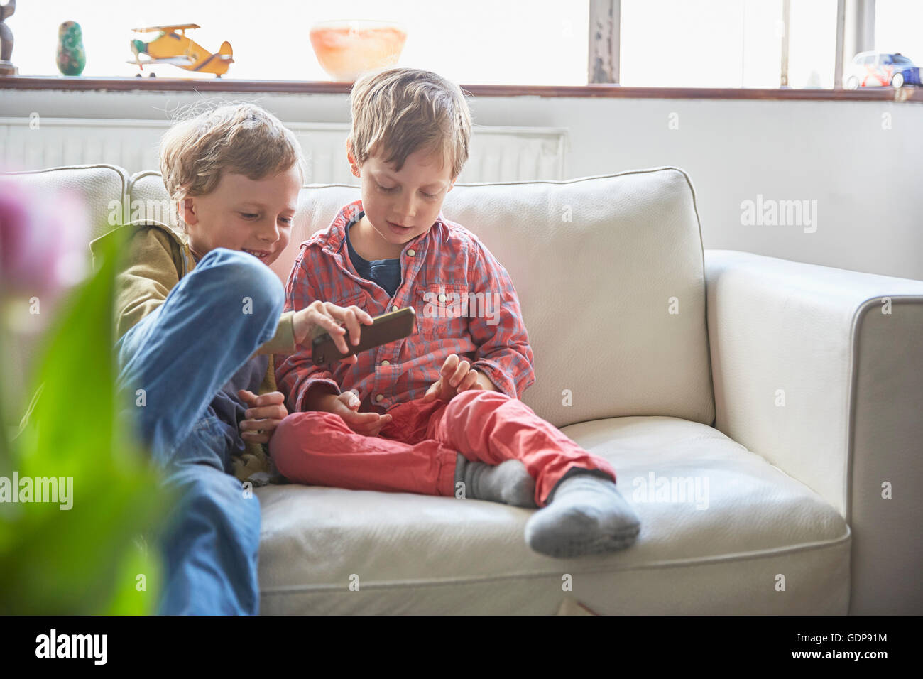 Boys sitting on sofa looking at smartphone Stock Photo - Alamy