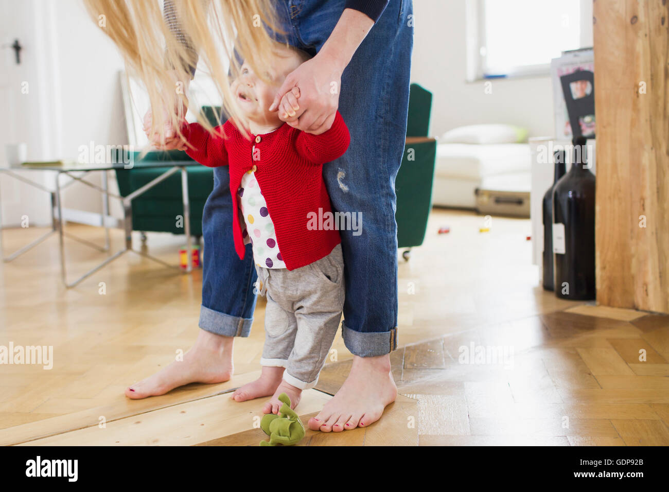 Baby girl holding mothers hands to take first steps Stock Photo