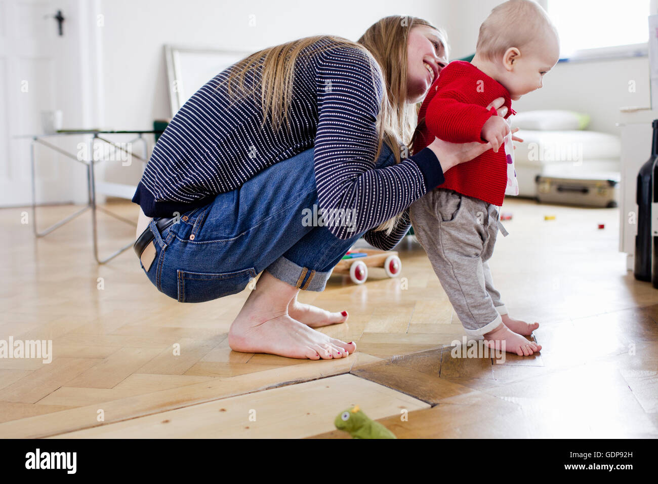Mid adult woman holding baby daughter to take first steps Stock Photo