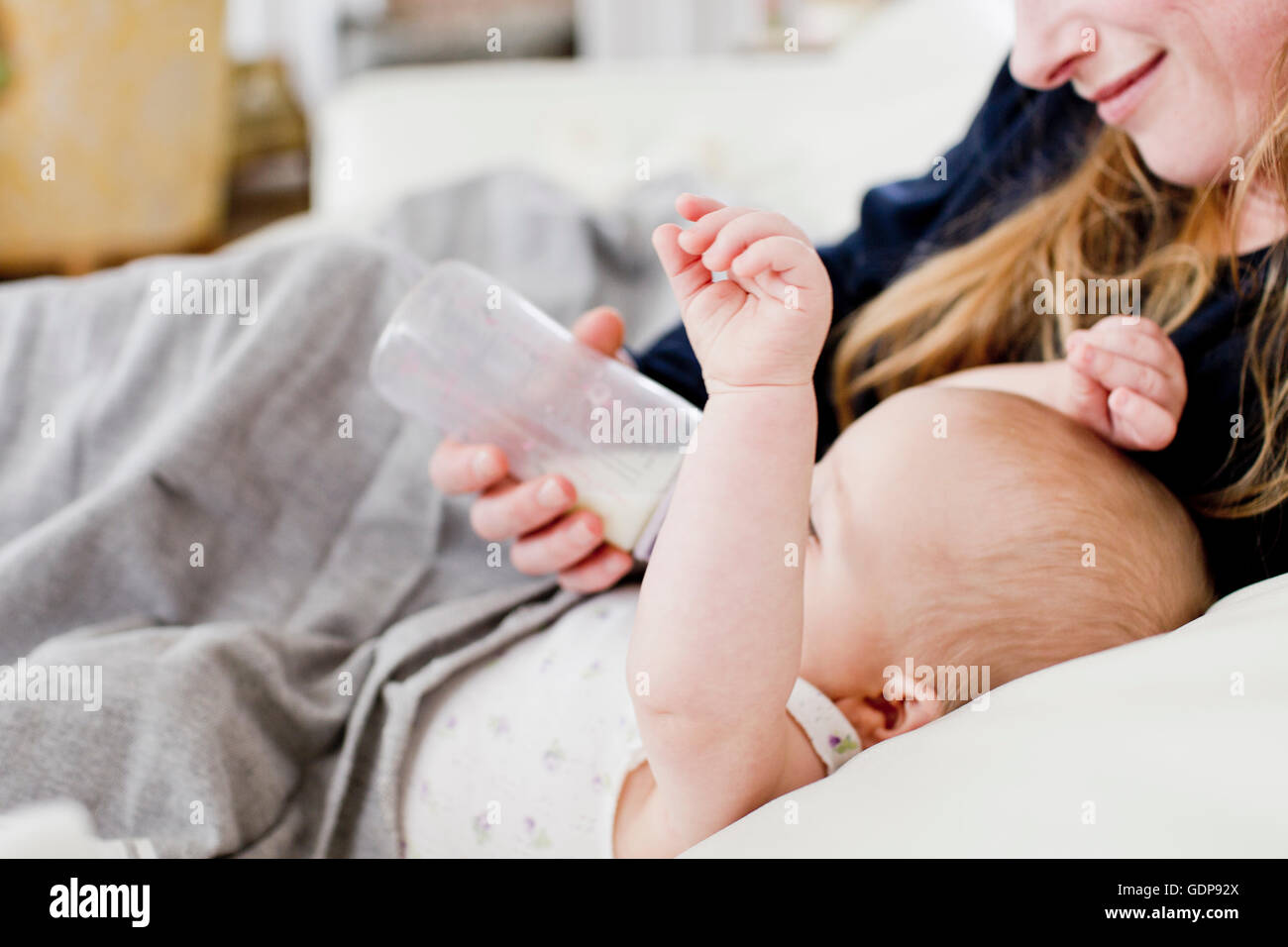 Close up of mid adult woman feeding baby daughter on sofa Stock Photo