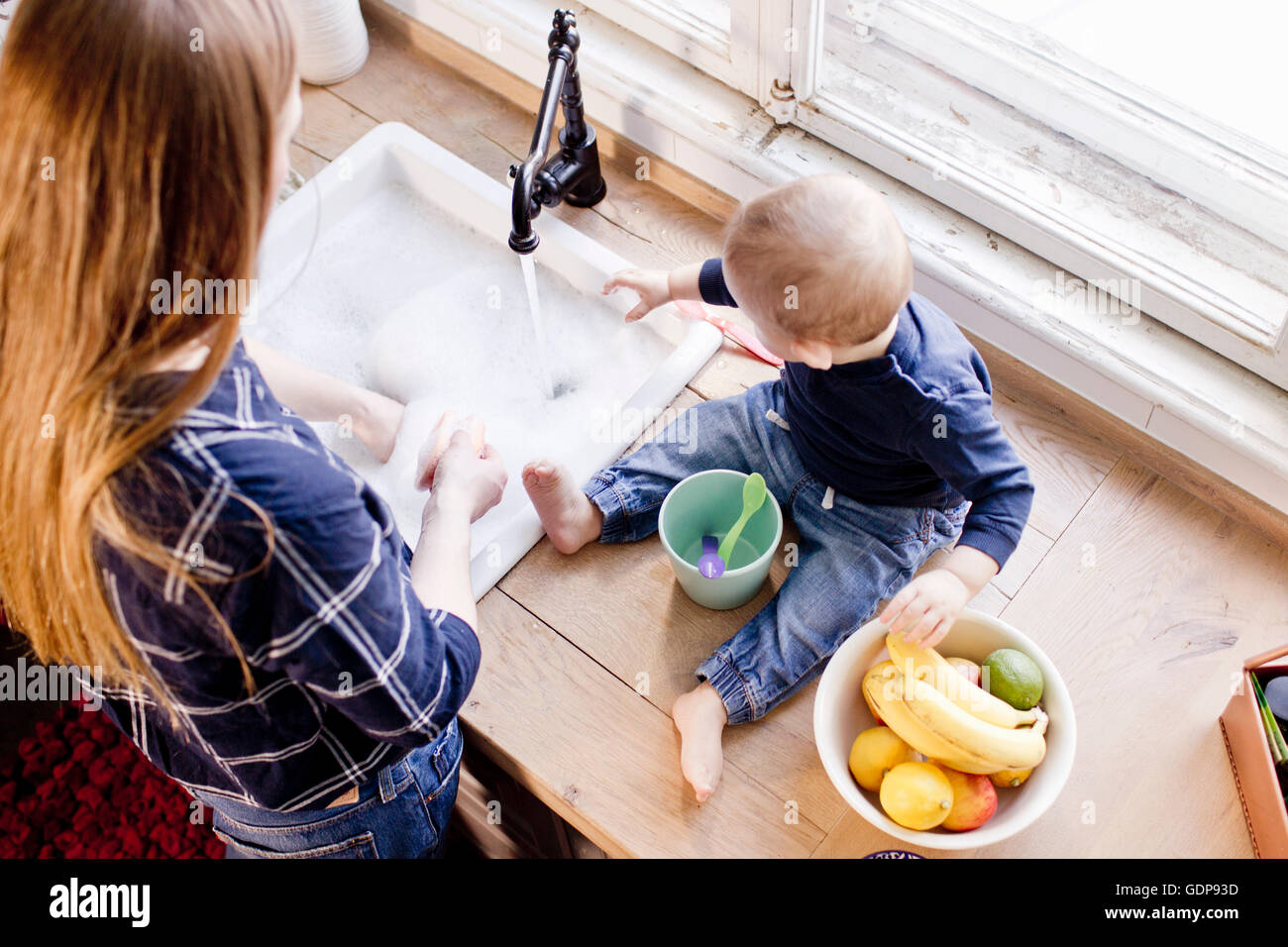 Overhead view of woman at kitchen sink with baby son Stock Photo