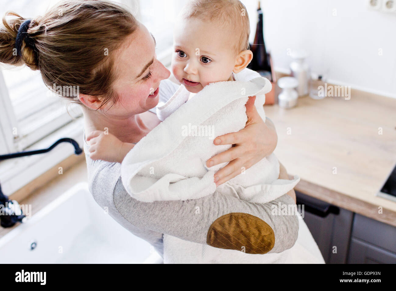 Mother carrying baby son wrapped in towel Stock Photo