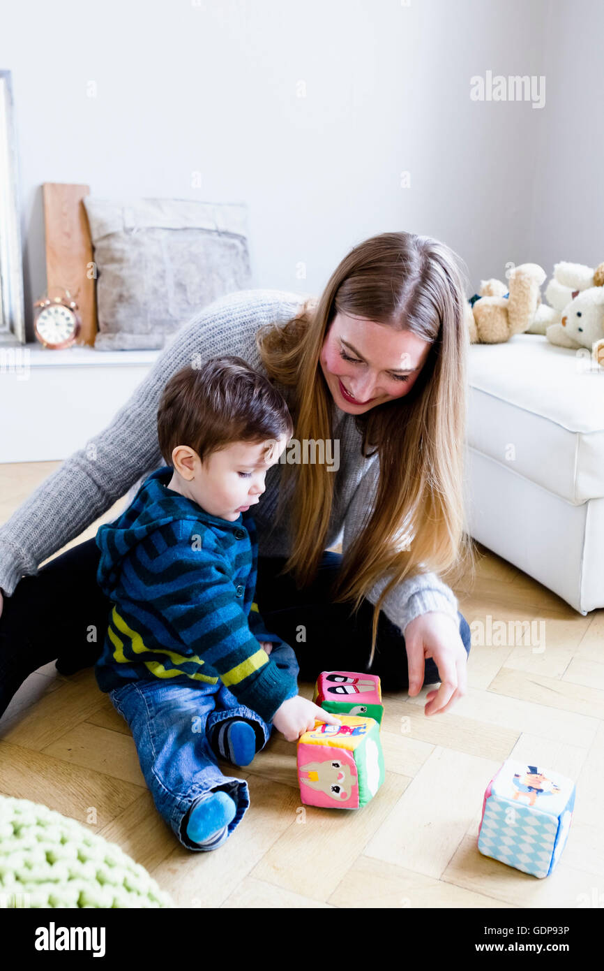 Mid adult woman playing with baby son on playroom floor Stock Photo