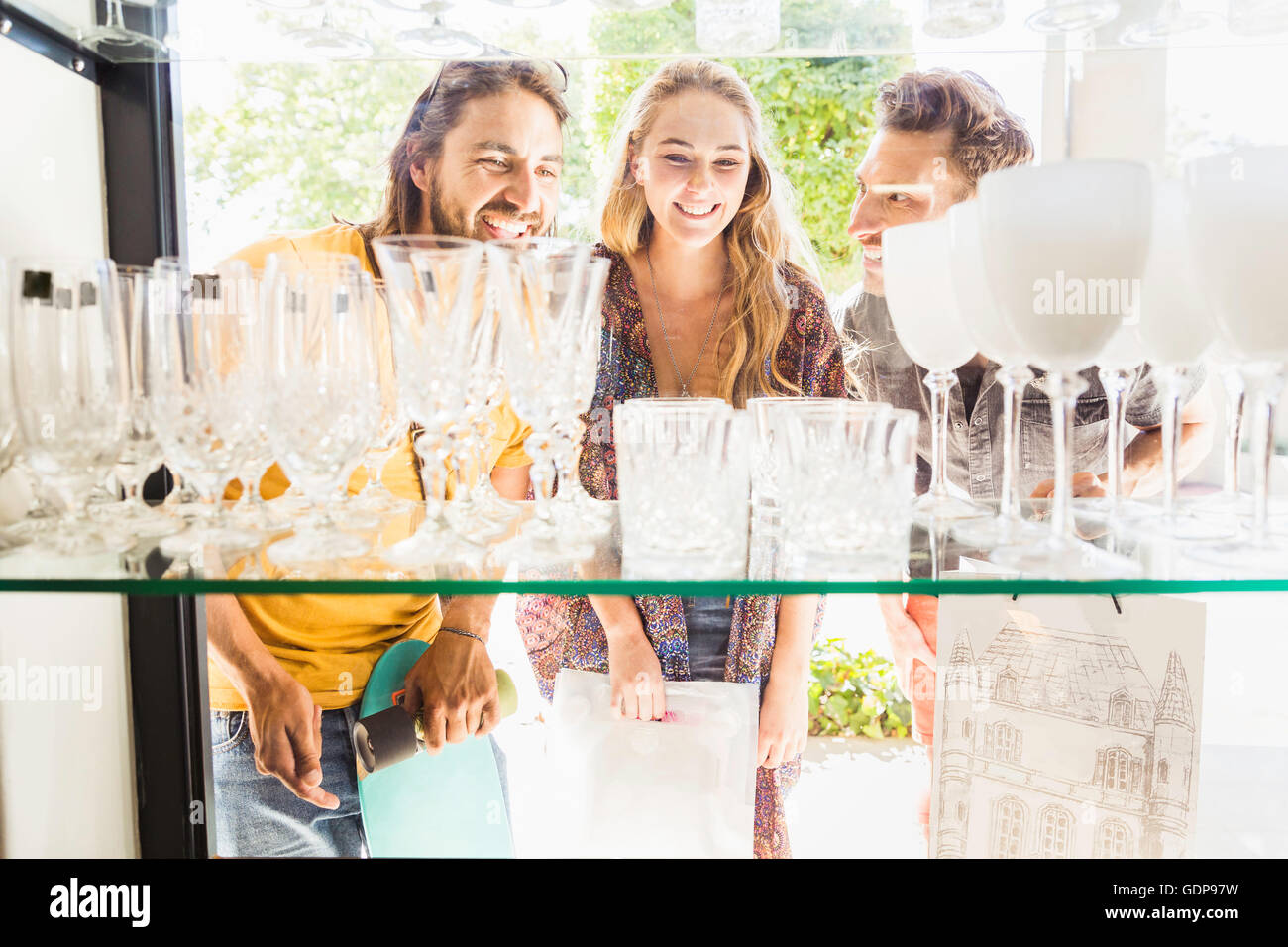 Three adult friends looking at drinking glasses through shop window
